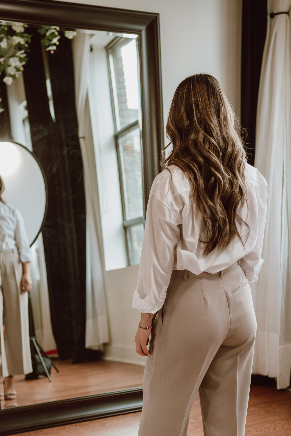 A photo of a woman standing in front of a mirror looking at herself for a blog post about 5 Ways To Silence Your Inner Critic